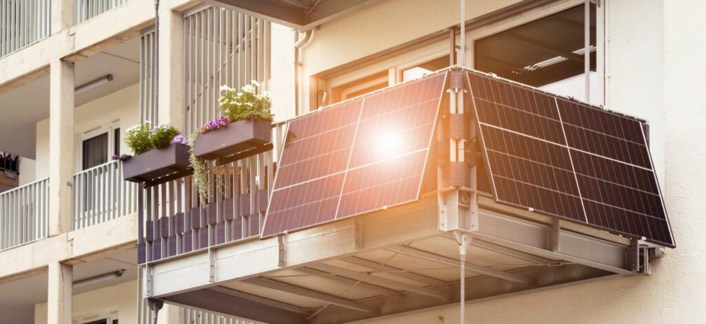 Ein Balkonkraftwerk hängt an einem Balkon eines Mehrfamilienhauses.