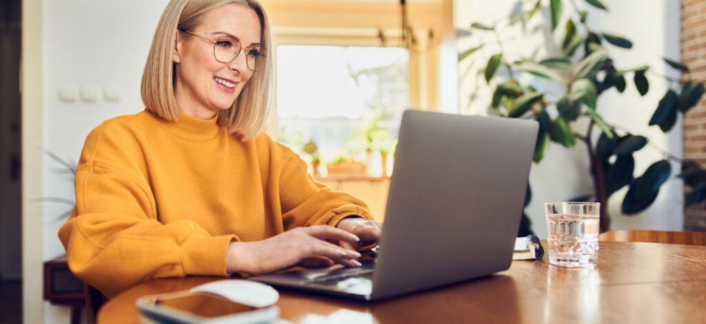 Eine Frau sitzt glücklich am Laptop.