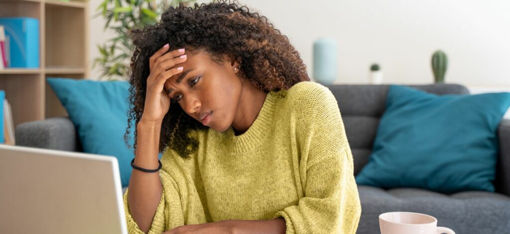 Eine Frau sitzt vor dem Laptop und guckt verzweifelt.