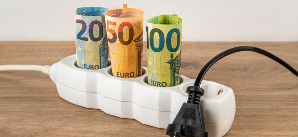 Mehrere gerollte Geldscheine stecken in einer Mehrfachsteckdose.