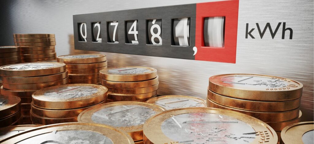 Mehrere Stapel Euromünzen stehen vor einem alten Stromzähler.