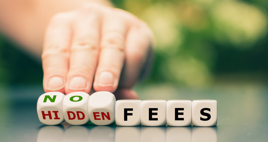 Eine Hand dreht Würfel um, auf denen "No fees" und "Hidden fees" steht.