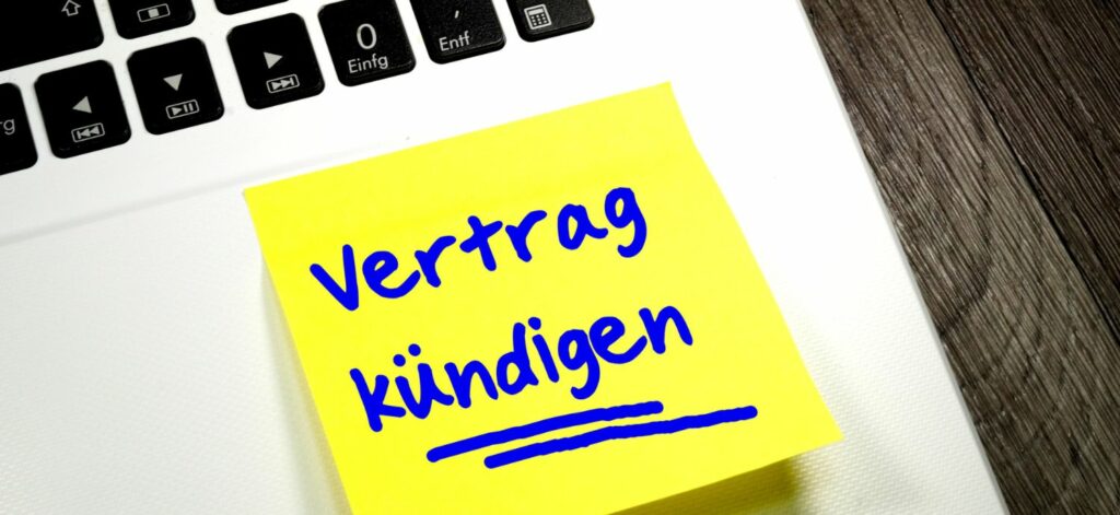Ein Post-It, auf dem "Vertrag kündigen" steht, klebt auf einem MacBook.